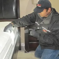 Bed bug inspection technician checking a mattress and bed frame for signs of infestation in San Antonio, TX